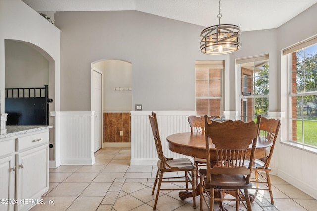 tiled dining area featuring lofted ceiling, a chandelier, and plenty of natural light