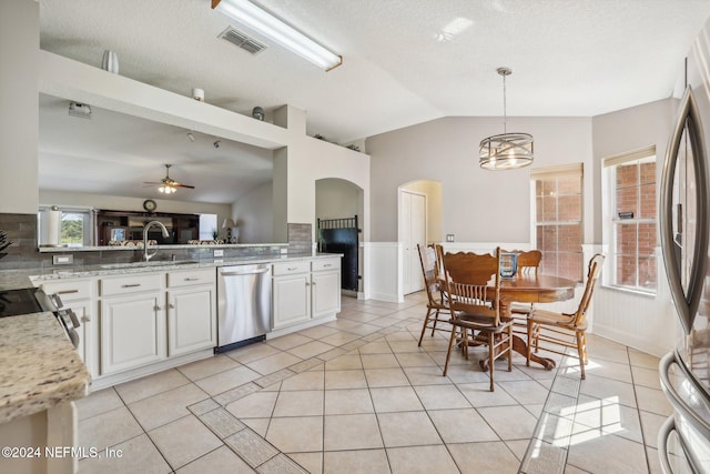 kitchen featuring white cabinets, hanging light fixtures, appliances with stainless steel finishes, vaulted ceiling, and ceiling fan with notable chandelier