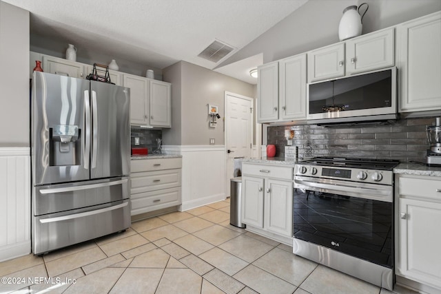 kitchen with appliances with stainless steel finishes, white cabinetry, and tasteful backsplash