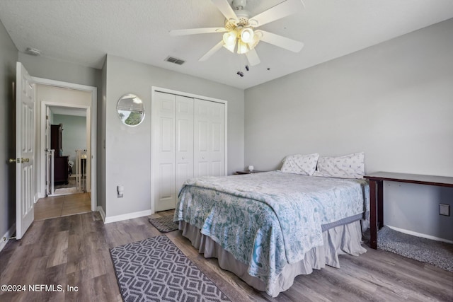 bedroom with a textured ceiling, hardwood / wood-style flooring, a closet, and ceiling fan