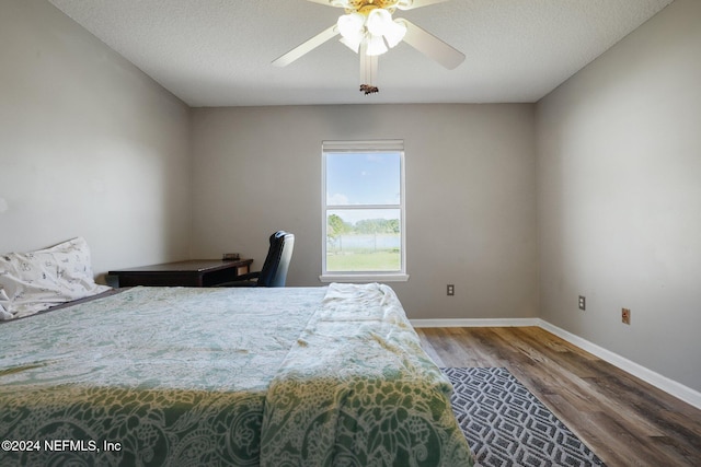 bedroom with ceiling fan, wood-type flooring, and a textured ceiling