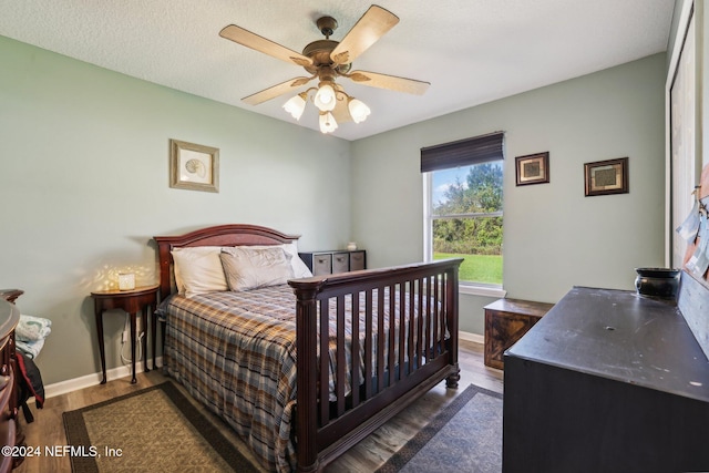 bedroom featuring ceiling fan, a textured ceiling, and dark hardwood / wood-style floors