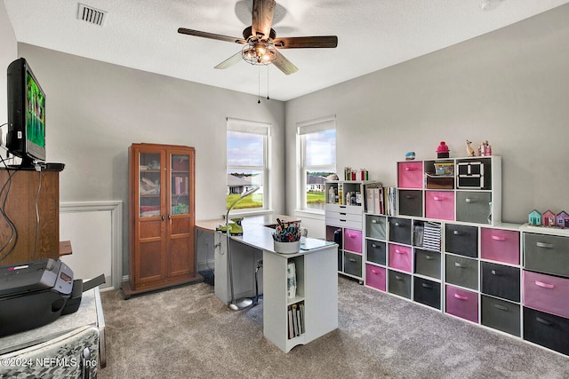 carpeted office with a textured ceiling and ceiling fan