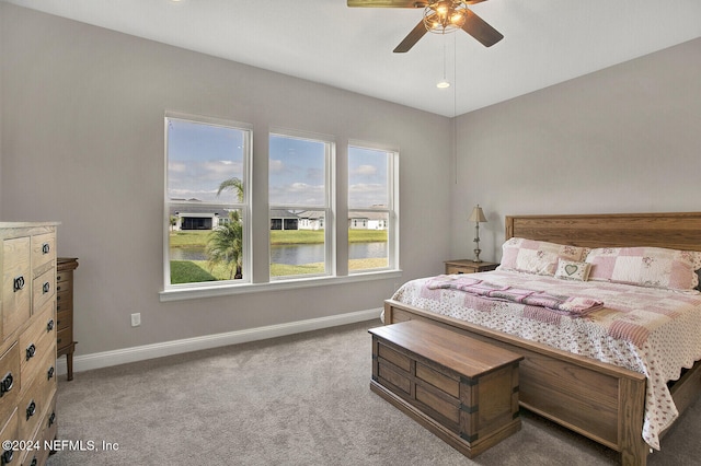 carpeted bedroom with baseboards, a water view, and ceiling fan