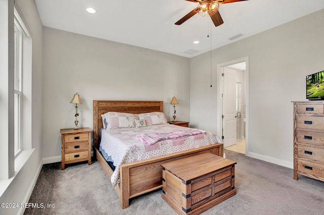 bedroom with light carpet, multiple windows, connected bathroom, and ceiling fan