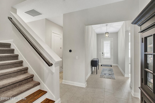 entrance foyer featuring stairway, baseboards, light tile patterned flooring, and visible vents