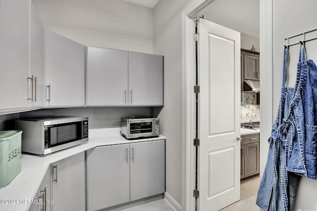 kitchen with under cabinet range hood, light countertops, a toaster, and stainless steel microwave