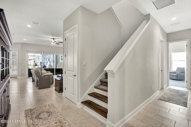 stairs with recessed lighting, a textured ceiling, baseboards, a ceiling fan, and visible vents