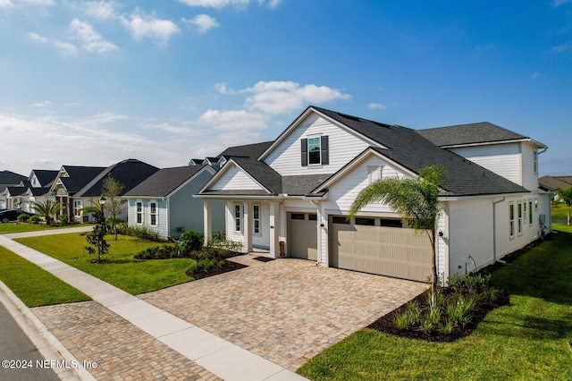 view of front of home featuring decorative driveway, a residential view, a front lawn, and a shingled roof