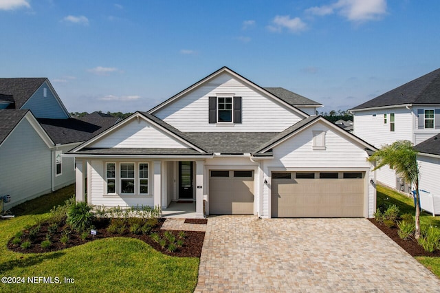 view of front of house with a front lawn, roof with shingles, and decorative driveway