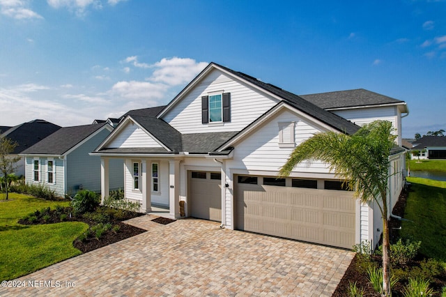 view of front of house with a shingled roof, a front lawn, and decorative driveway