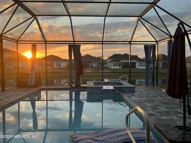 pool at dusk with a patio, a pool with connected hot tub, glass enclosure, and a residential view