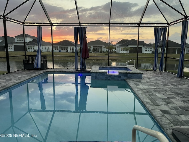 pool at dusk featuring glass enclosure, a residential view, and a water view