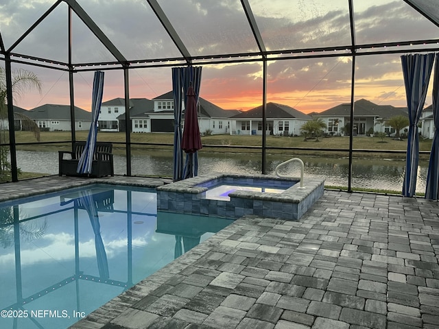 pool at dusk with glass enclosure, a residential view, a patio, and a water view