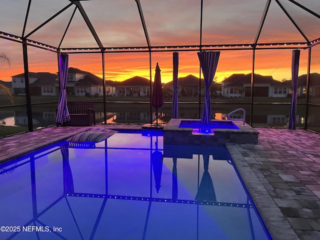 pool at dusk with a pool with connected hot tub, a patio, and a residential view