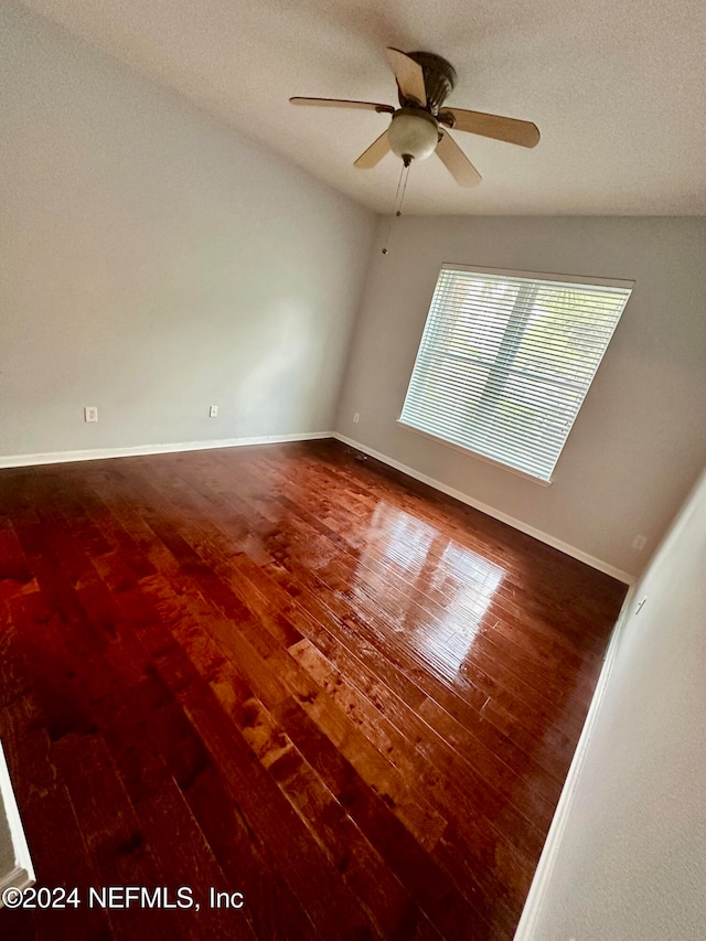 empty room with a textured ceiling, hardwood / wood-style flooring, ceiling fan, and vaulted ceiling