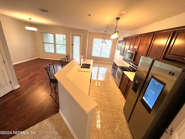 kitchen with light hardwood / wood-style floors, stainless steel appliances, sink, and pendant lighting