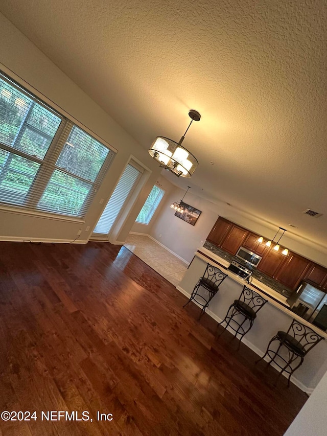 unfurnished living room with an inviting chandelier, a textured ceiling, and a healthy amount of sunlight