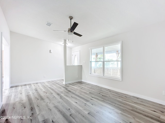 empty room with a textured ceiling, light wood-type flooring, and ceiling fan