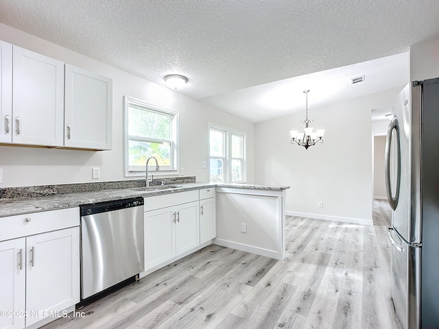 kitchen with appliances with stainless steel finishes, white cabinets, and light hardwood / wood-style floors