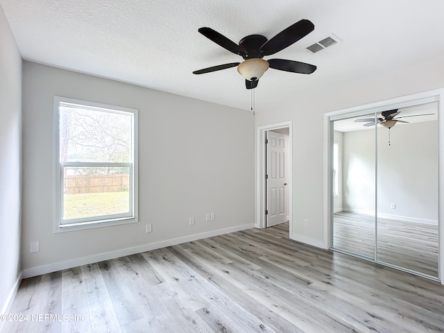 empty room with light hardwood / wood-style flooring, a textured ceiling, and ceiling fan