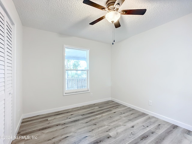 unfurnished room featuring a textured ceiling, light wood-type flooring, and ceiling fan