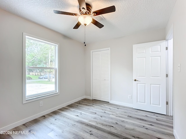 unfurnished bedroom featuring a closet, ceiling fan, a textured ceiling, and light wood-type flooring