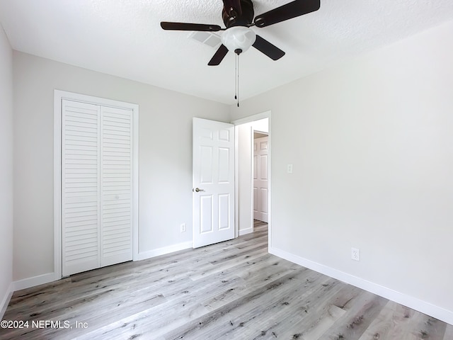 unfurnished bedroom with light hardwood / wood-style flooring, a textured ceiling, a closet, and ceiling fan