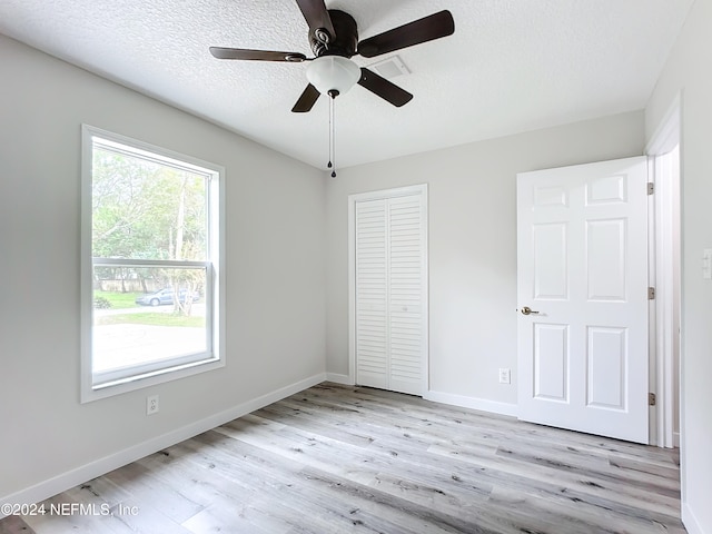 unfurnished bedroom with multiple windows, light wood-type flooring, and ceiling fan