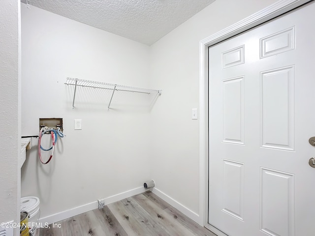 laundry room featuring light hardwood / wood-style flooring, a textured ceiling, and washer hookup