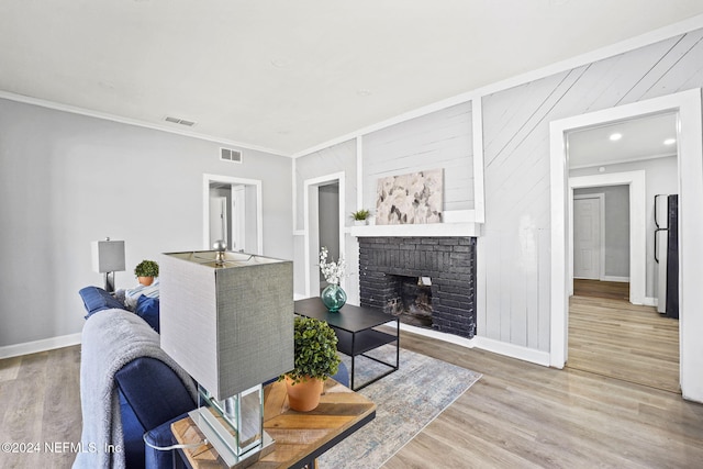 living room featuring hardwood / wood-style flooring, wood walls, crown molding, and a brick fireplace