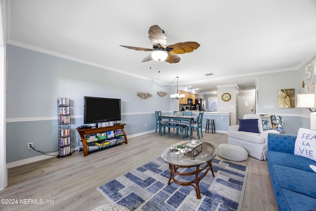 living room featuring ceiling fan with notable chandelier, crown molding, and light wood-type flooring