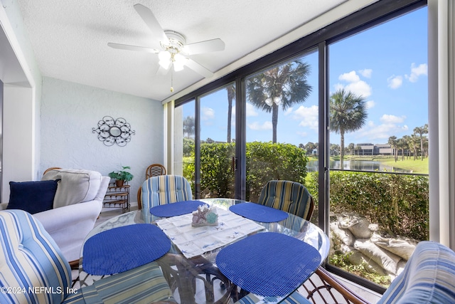 dining area with a textured ceiling, a water view, and ceiling fan