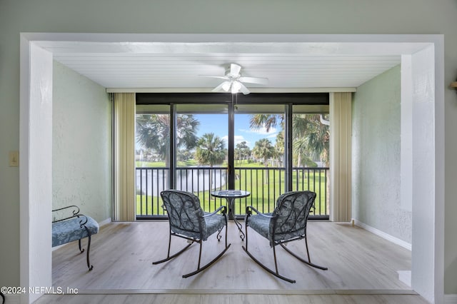 sunroom / solarium with a water view and ceiling fan