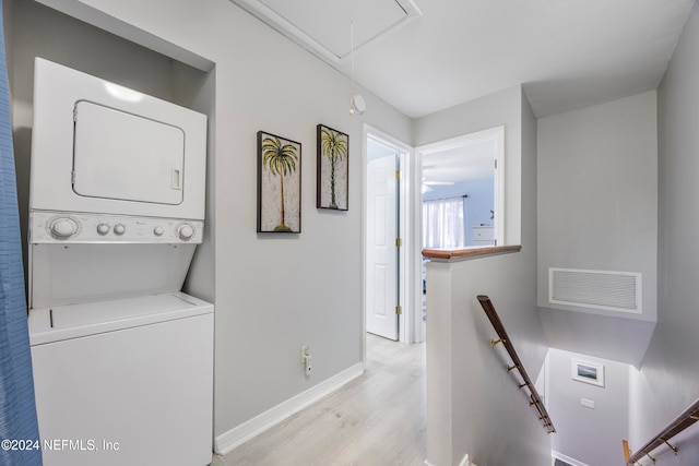 laundry area with light hardwood / wood-style floors and stacked washer and dryer