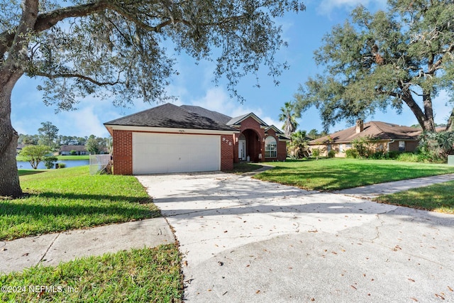 ranch-style house with a garage, a front lawn, and a water view