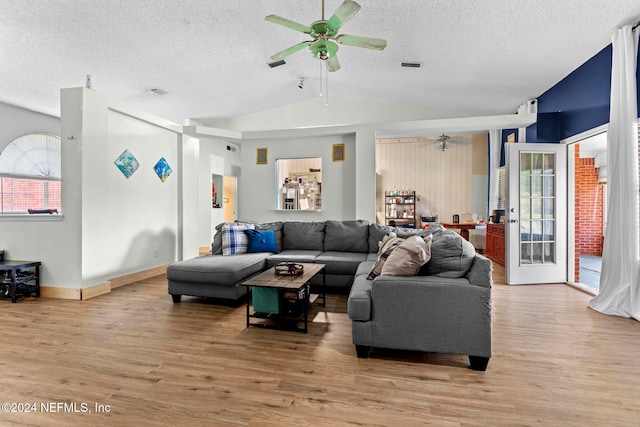 living room featuring a textured ceiling, wood-type flooring, vaulted ceiling, and ceiling fan