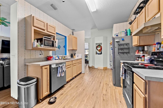 kitchen with light brown cabinetry, sink, appliances with stainless steel finishes, light wood-type flooring, and a textured ceiling