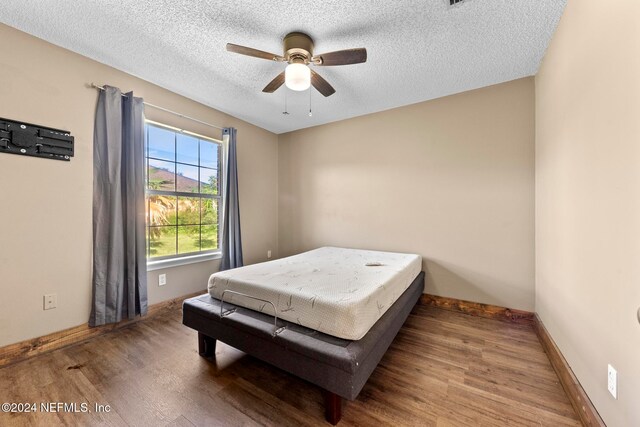 bedroom with a textured ceiling, hardwood / wood-style flooring, and ceiling fan