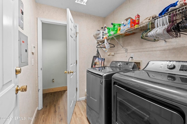 washroom with light hardwood / wood-style floors, electric panel, and washer and dryer