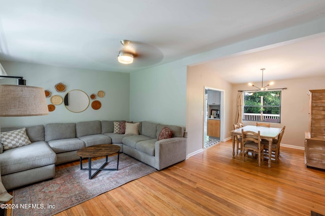 living room featuring ceiling fan with notable chandelier and light wood-type flooring