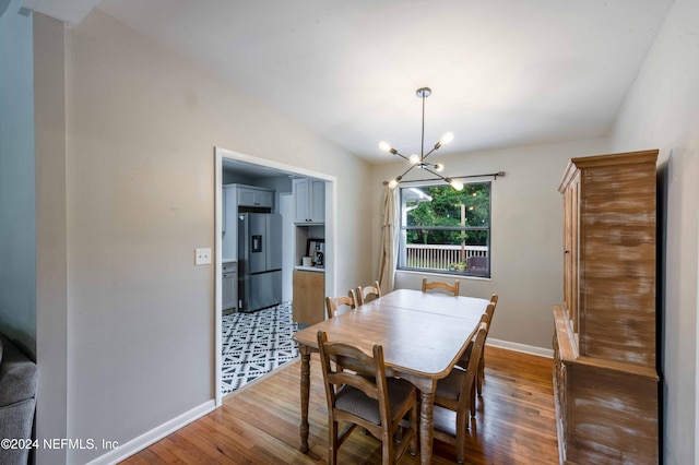 dining room featuring lofted ceiling, hardwood / wood-style floors, and a notable chandelier