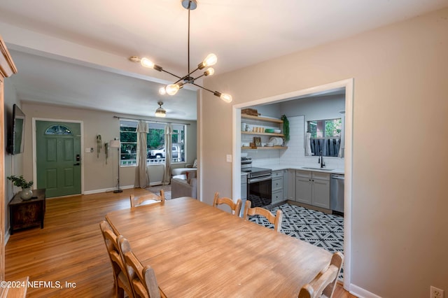 dining space featuring sink, a notable chandelier, and light wood-type flooring