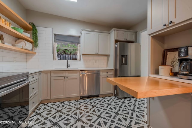 kitchen featuring sink, butcher block countertops, decorative backsplash, and stainless steel appliances