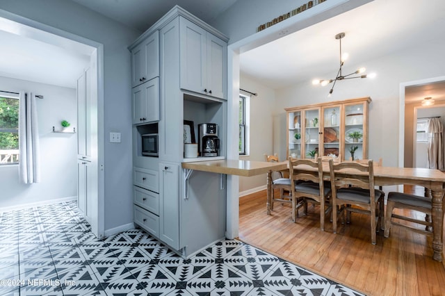 kitchen featuring gray cabinetry, light hardwood / wood-style floors, an inviting chandelier, and pendant lighting