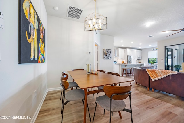 dining space with an inviting chandelier, light hardwood / wood-style flooring, and a textured ceiling