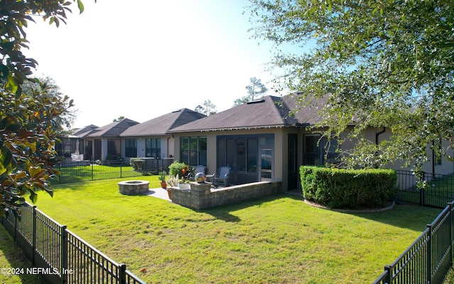 rear view of house featuring a yard, a patio area, and an outdoor fire pit