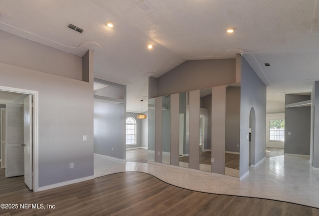 empty room with a healthy amount of sunlight, lofted ceiling, and light hardwood / wood-style flooring