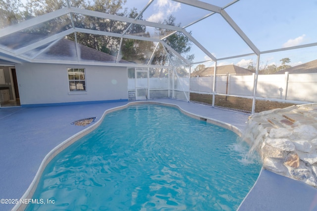 view of pool featuring glass enclosure, pool water feature, and a patio