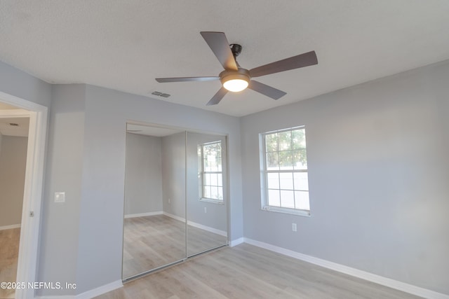 unfurnished bedroom with ceiling fan, light hardwood / wood-style floors, a textured ceiling, and a closet